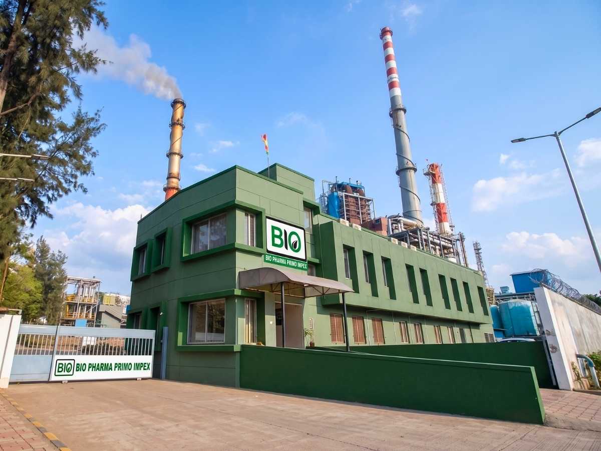 Exterior view of Bio Pharma Primo Impex certified pharmaceutical manufacturing plant building and industrial infrastructure with tall stacks under a clear sky.